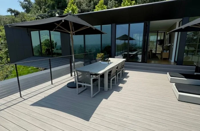 Modern TimberTech composite deck featuring glass safety railings and an outdoor dining area in Malibu.