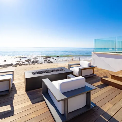 Beach house deck with a fire pit and comfortable loungers.