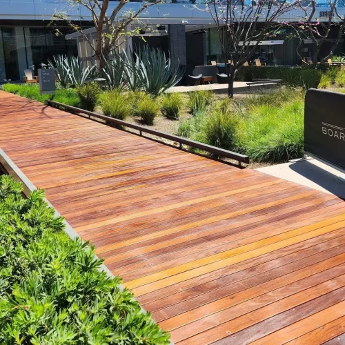 Expert commercial deck construction company in Los Angeles. Sunrise view from a boardBoardwalk deck with benches and shaded areas for relaxation.walk deck along a serene lake.